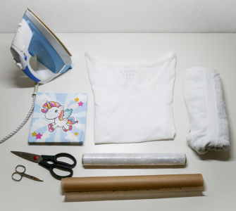 Serviertte mit Einhorn, weißes T-Shirt, Frischhaltefolie, Backpapier, eine große und kleine Schere und ein Bügeleisen