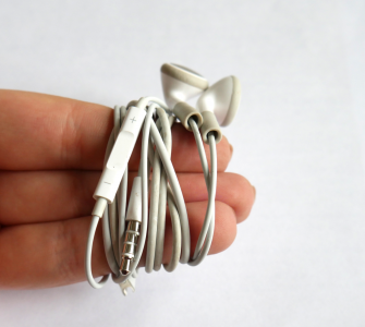 Zeige-, Mittel- und Ringfinger mit aufgewickeltem Kopfhörer-Kabel