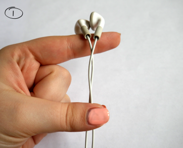 Daumen und kleiner Finger halten Kopfhörerkabel fest, Kopfhörer selber liegen auf Zeigefinger
