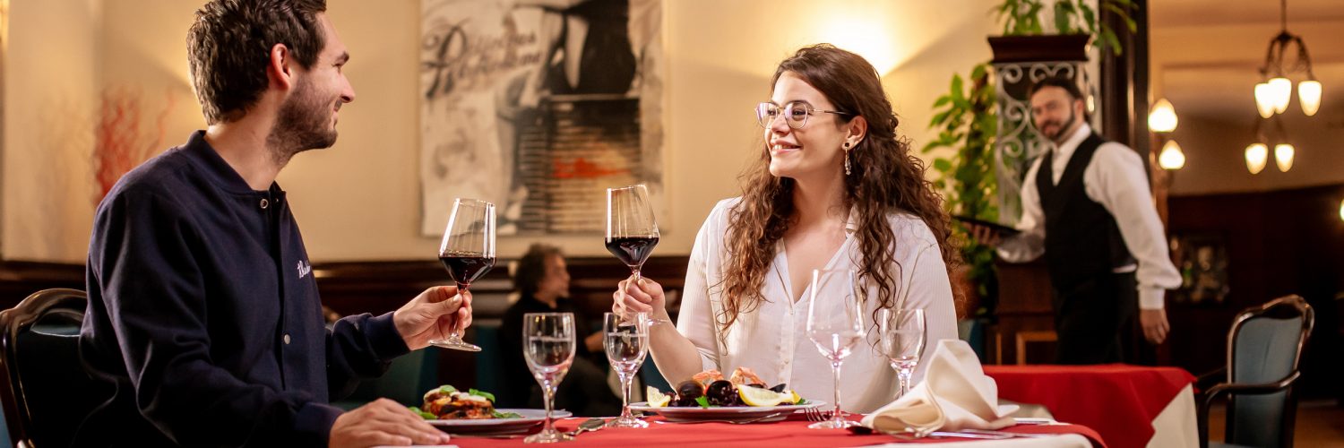 Paar an einem Restaurant Tisch mit Wein in der Hand