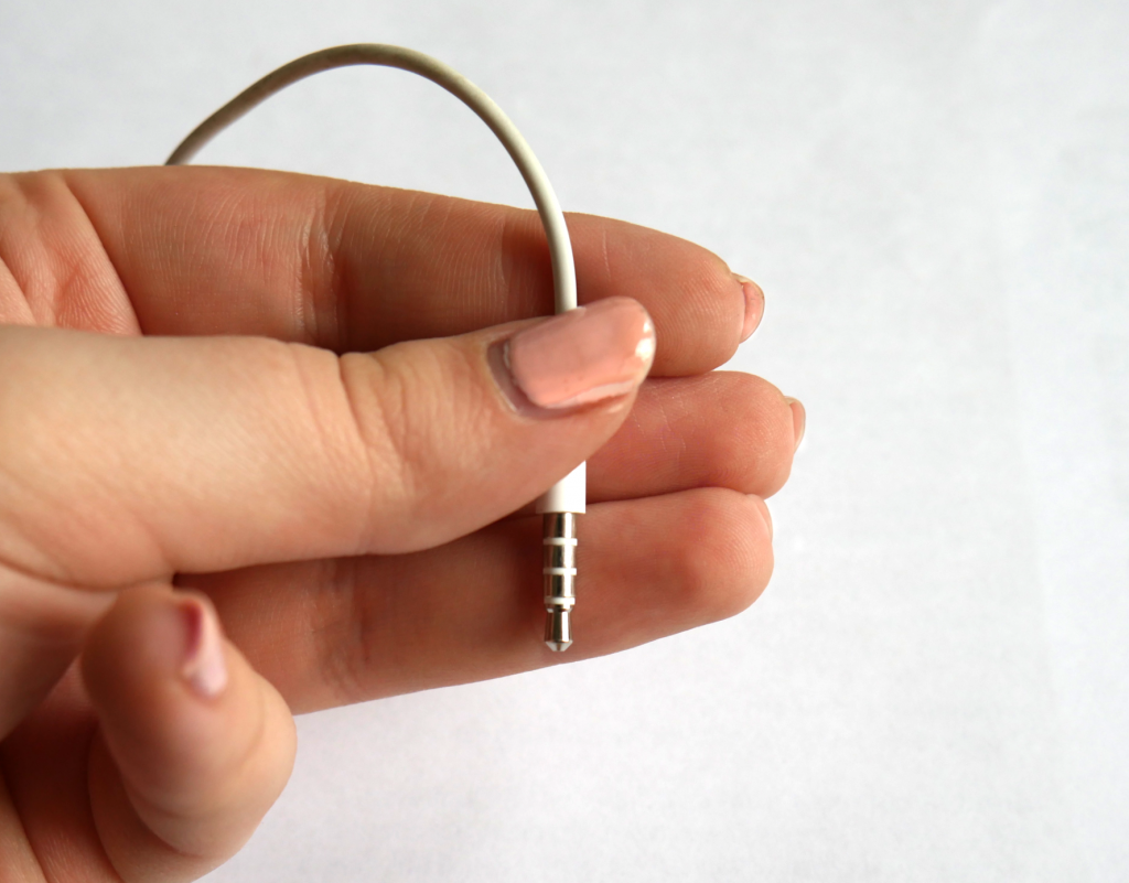 Daumen, Zeige-, Mittel-, und Ringfinger halten den Anschluss der Kopfhörer