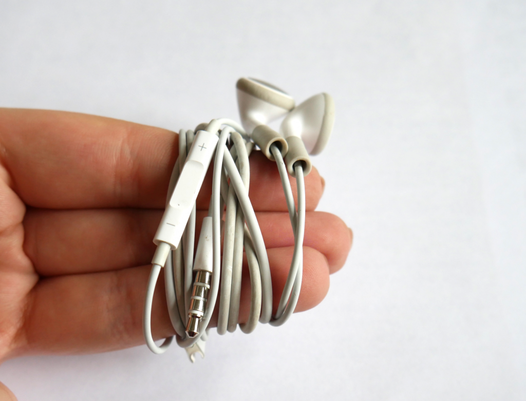 Zeige-, Mittel- und Ringfinger mit aufgewickeltem Kopfhörer-Kabel