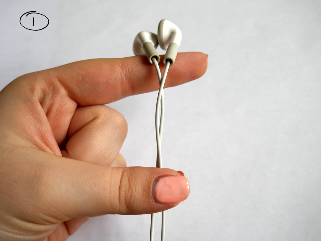 Daumen und kleiner Finger halten Kopfhörerkabel fest, Kopfhörer selber liegen auf Zeigefinger