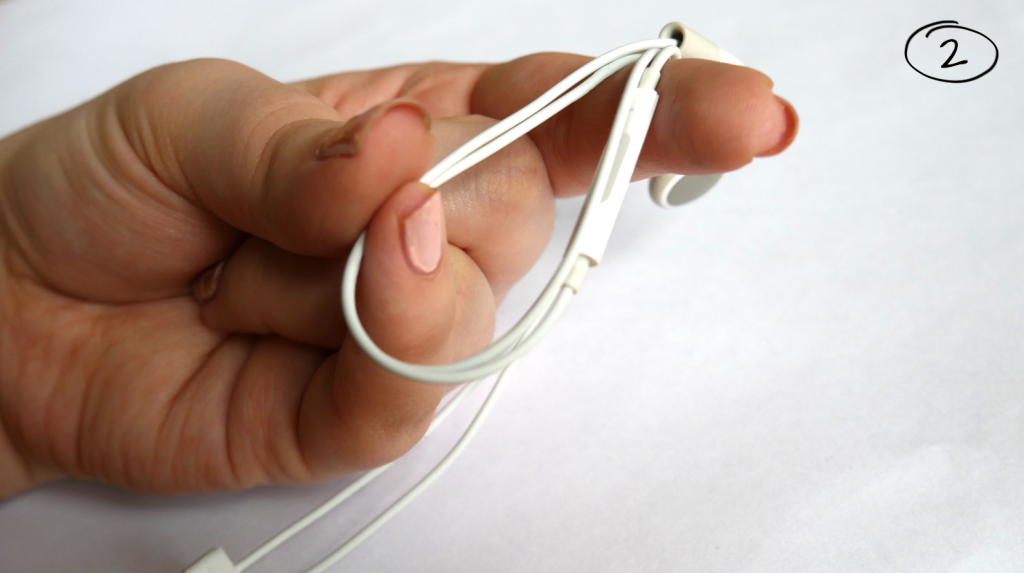 Daumen, kleiner Finger und Zeigefinger wickeln Kopfhörer auf