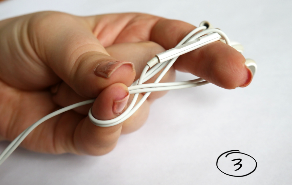 Daumen, kleiner Finger und Zeigefinger wickeln Kopfhörer Kabel auf