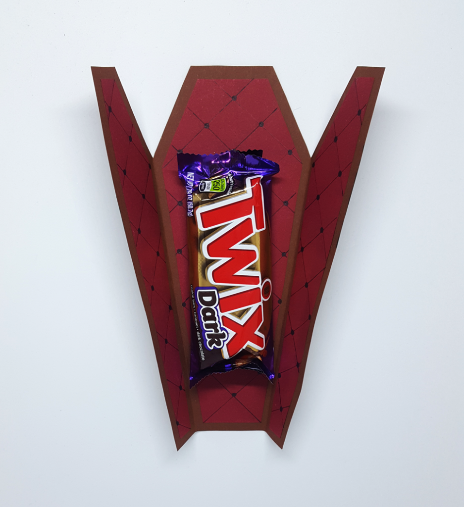 Ein Sarg aus Pappe mit einem Twix Dark