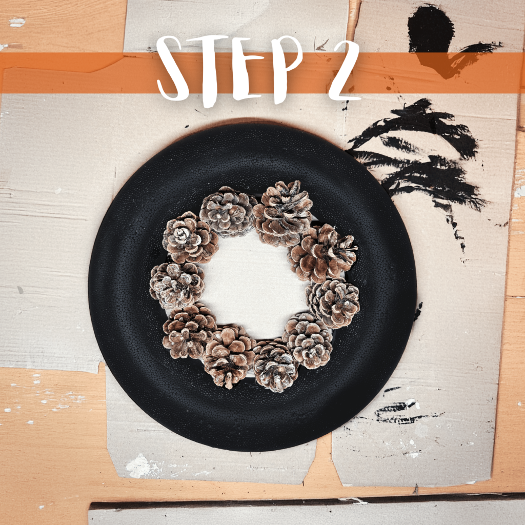 Die Tannenzapfen an dem Styroporring platzieren und mit Heißkleber fixieren